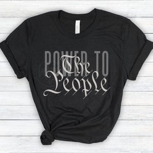 May include: Black t-shirt with the text "Power to the People" in a white, stylized font.