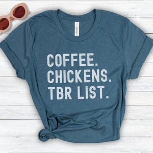 May include: A teal blue t-shirt with the text "COFFEE. CHICKENS. TBR LIST." printed in white.