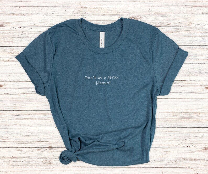 Peut inclure: T-shirt bleu sarcelle avec des manches retrouss&eacute;es. Le texte "Don't be a jerk. -[Jesus]" est imprim&eacute; en blanc. Le t-shirt est en mati&egrave;re souple et nou&eacute; en bas. V&ecirc;tement d&eacute;contract&eacute;.