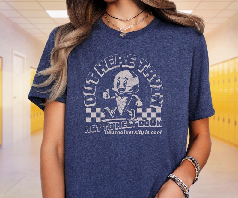 Puede incluir: Una camiseta azul con un gr&aacute;fico de un cono de helado de dibujos animados con una cara y el texto "Out Here Tryin' Not To Melt Down" y "Neurodiversity is cool".