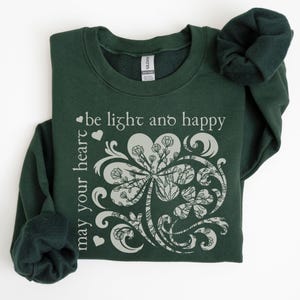 May include: A dark green sweatshirt with a white shamrock design and the text "may your heart be light and happy".