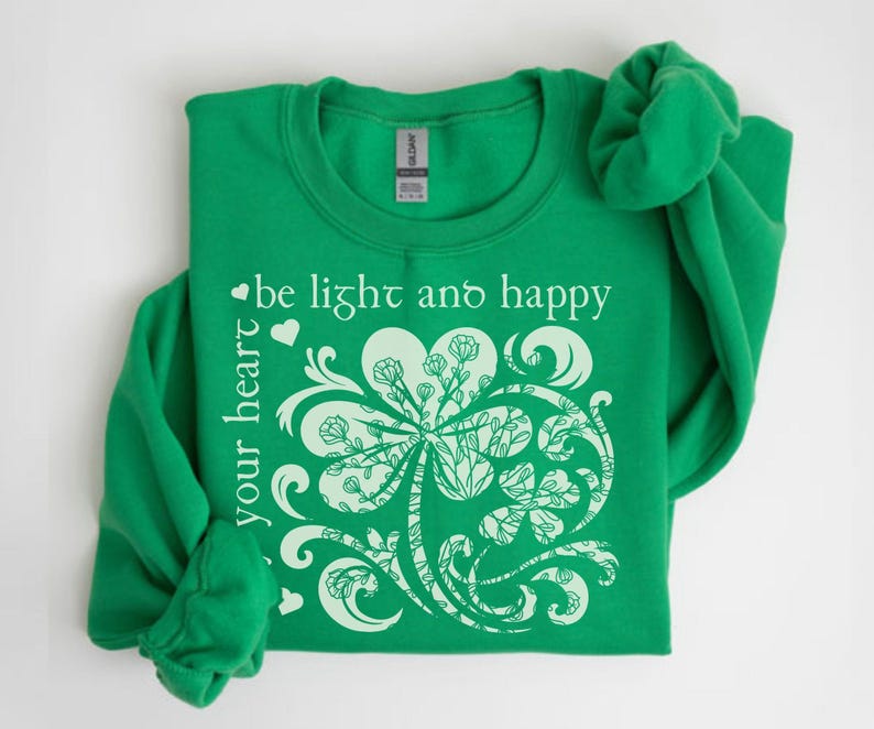 May include: Green sweatshirt with a white shamrock design and the text "be light and happy your heart".
