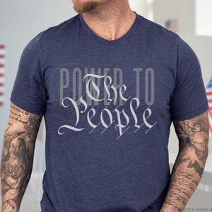 May include: A navy blue t-shirt with a white graphic that says "Power to the People" in a stylized font.