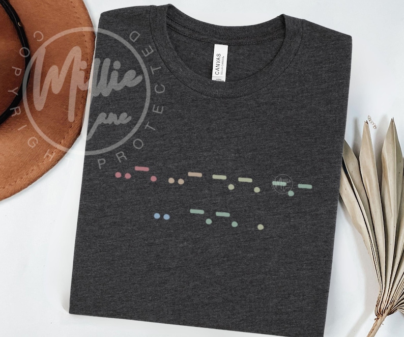 May include: Dark gray t-shirt with a colorful Morse code design. The shirt features a crew neck and short sleeves. The Morse code is in pastel colors and is printed across the chest.