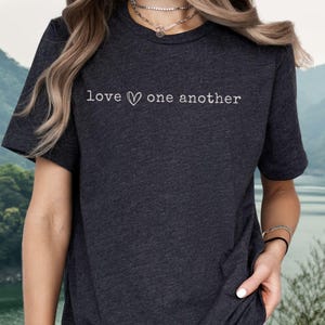 May include: A dark gray t-shirt with the text "love ♥ one another" printed in white on the front.