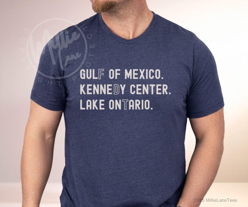May include: A heathered navy blue short-sleeve t-shirt featuring white text that reads GULF OF MEXICO, KENNEDY CENTER, and LAKE ONTARIO. The letters F, D, and T are highlighted in a different font style within the words on the shirt.