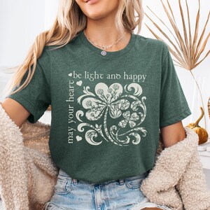 May include: A green t-shirt with a white shamrock design and the text "may your heart be light and happy".