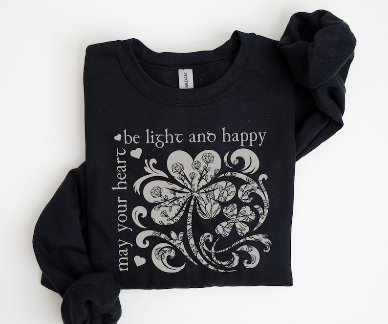 May include: Black sweatshirt with a white graphic of a stylized four-leaf clover with the text "may your heart be light and happy".