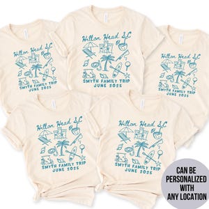 May include: Four beige t-shirts with a blue graphic design of a palm tree, beach umbrella, beach chairs, and other beach-related items. The text "Hilton Head SC" and "Smyth Family Trip June 2025" is printed on each shirt.