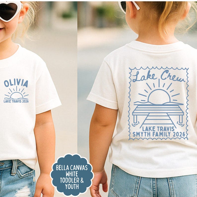 May include: A white short-sleeved t-shirt featuring blue graphics. The front displays the name OLIVIA above a sun icon and the text LAKE TRAVIS 2026. The back shows a stamp-shaped design with a dock, sun, and the text Lake Crew LAKE TRAVIS SMYTH FAMILY 2026.