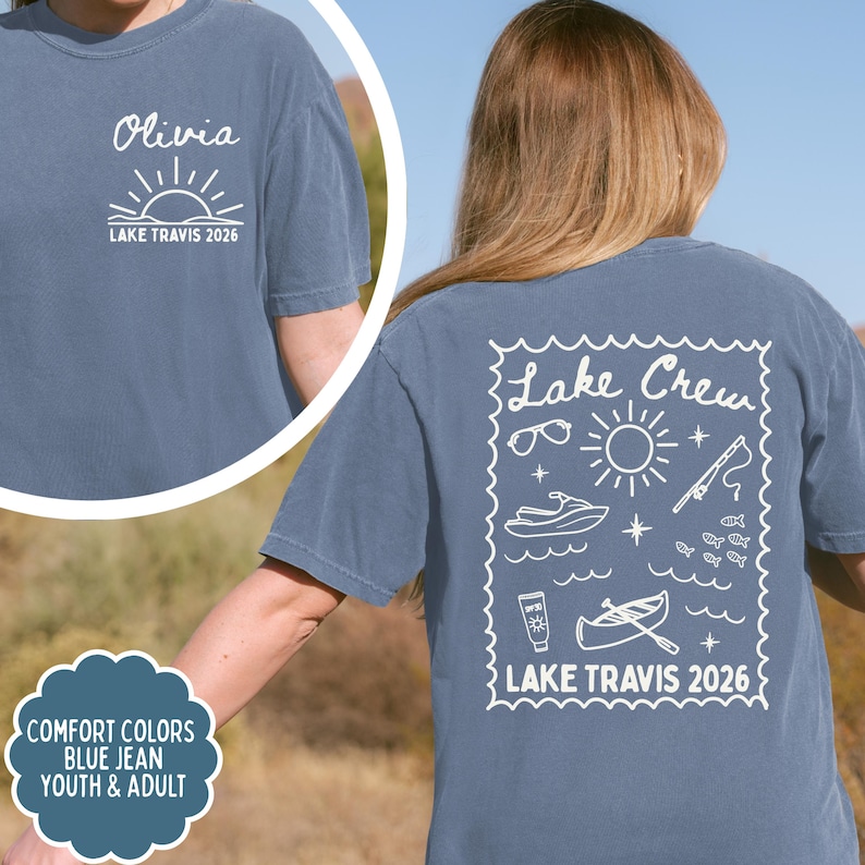 May include: Blue jean Comfort Colors t-shirt with white graphics. The front features the name "Olivia" above a sun design and "LAKE TRAVIS 2026". The back displays "Lake Crew" with lake-themed illustrations and "LAKE TRAVIS 2026".