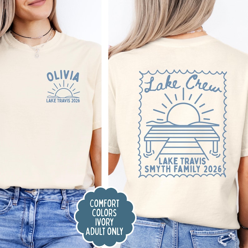 May include: An ivory t-shirt featuring blue graphics. The front displays the name OLIVIA above a sun icon and the text LAKE TRAVIS 2026. The back shows a large stamp-shaped design with a sun over a dock, the text Lake Crew, and LAKE TRAVIS SMYTH FAMILY 2026.