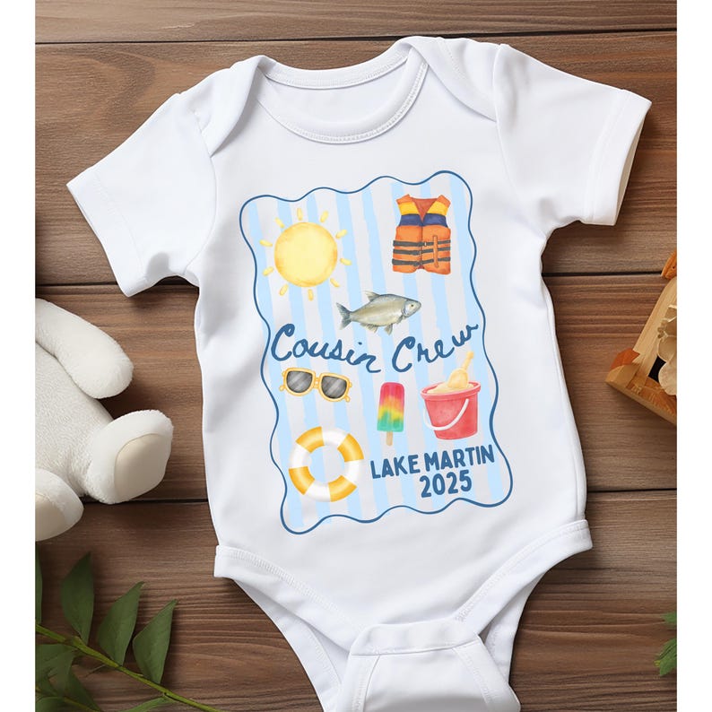 May include: White baby onesie with a blue and yellow graphic. The graphic includes a sun, life vest, fish, sunglasses, popsicle, bucket of ice cream, and a life preserver. Text reads "Cousin Crew Lake Martin 2025."