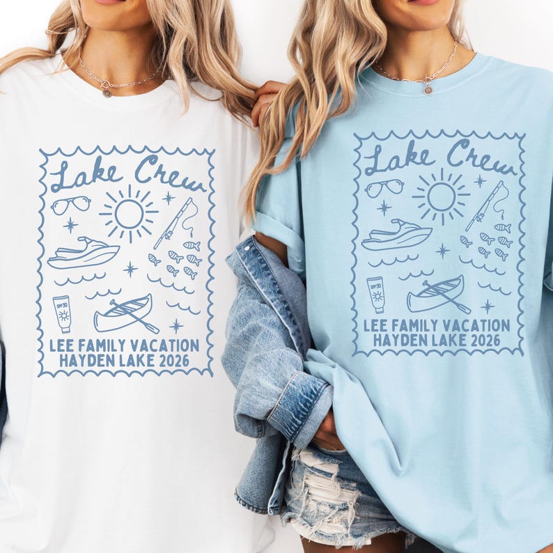 May include: White and light blue t-shirts with a blue graphic design. The design includes the text "Lake Crew" and illustrations of sunglasses, a sun, a jet ski, fish, sunscreen, and a canoe. The text "LEE FAMILY VACATION HAYDEN LAKE 2026" is also included.