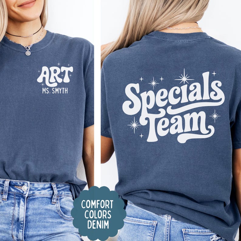 以下が含まれることがあります： デニムブルーのTシャツで、白いスクリーンプリントの文字が特徴です。前面には「ART」と「MS. SMYTH」の文字と小さな星のアクセントがあります。背面には、大きなスタイリッシュなフォントで「Specials Team」という文字が書かれ、いくつかの星のアイコンで囲まれています。