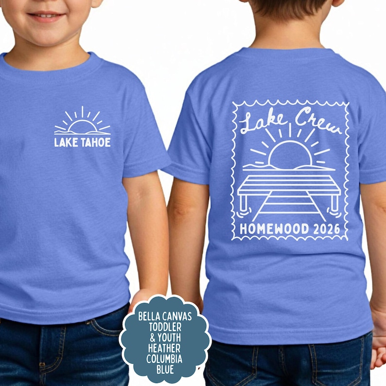 May include: A heather blue t-shirt featuring a white graphic of a sun over water and the text LAKE TAHOE on the front. The back displays a larger white graphic of a sun, a dock, and the text Lake Crew HOMEWOOD 2026 inside a stamp border.