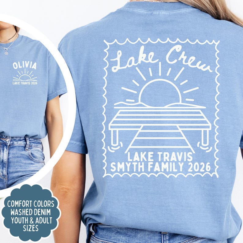 May include: A denim blue t-shirt featuring a white graphic on the back of a dock, sun, and the text Lake Crew, Lake Travis Smyth Family 2026. The front chest area displays the text Olivia, Lake Travis 2026 with a small sun graphic.