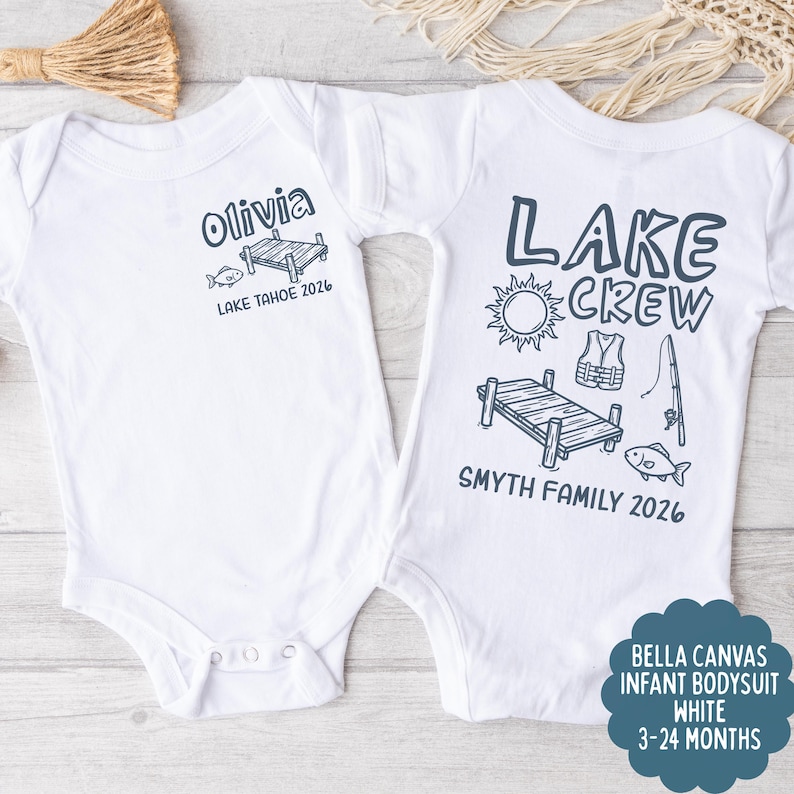 May include: Two white infant bodysuits. One says "Olivia" with a dock and fish graphic, "Lake Tahoe 2026". The other says "Lake Crew" with sun, life vest, fishing pole, dock, and fish graphic, "Smyth Family 2026".
