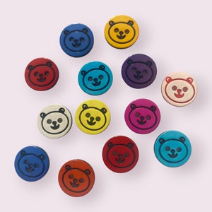 May include: Assortment of 13 colourful bear-shaped buttons with black outlines. The buttons are in various colours, including red, blue, yellow, green, purple, and white.