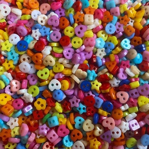 May include: A large assortment of colourful plastic buttons in various shapes, including hearts, stars, and circles. The buttons have two holes and are ideal for crafting projects.