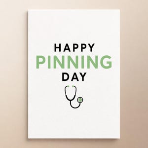 Może przedstawiać: Biała prostokątna kartka z czarnym napisem HAPPY i DAY oraz wyśrodkowanym między nimi słowem PINNING w kolorze jasnej zieleni. Poniżej tekstu znajduje się prosty czarno-jasnozielony rysunek liniowy stetoskopu medycznego.