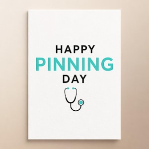Może przedstawiać: Biała prostokątna kartka z czarnym napisem HAPPY i DAY oraz słowem PINNING zapisanym dużymi turkusowymi literami. Poniżej tekstu znajduje się czarno-turkusowa graficzna ilustracja stetoskopu medycznego umieszczona na środku.