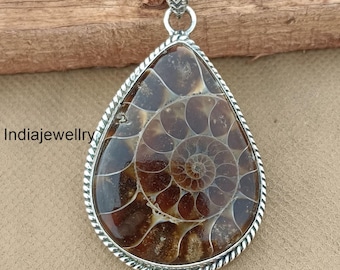 May include: A silver pendant featuring a fossilized ammonite with a brown and white spiral pattern. The pendant is set in a teardrop-shaped silver frame with a rope-like border.