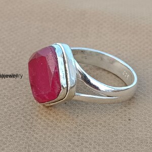 Op de afbeelding: Een zilveren ring met een rode edelsteen in een vierkante zetting. De ring heeft een gespleten band.