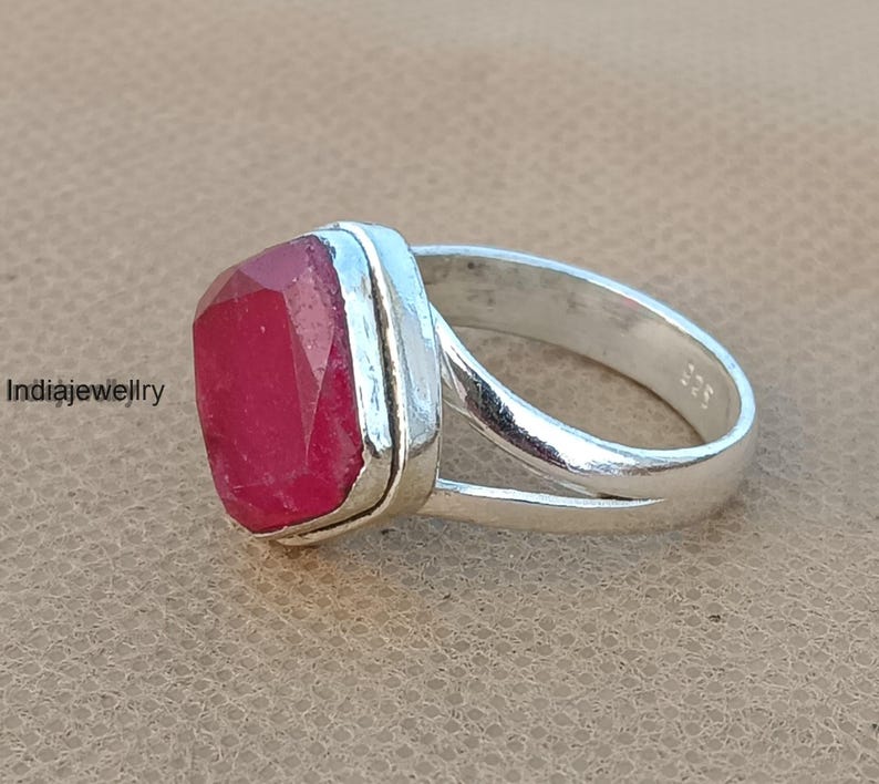 Op de afbeelding: Een zilveren ring met een rode edelsteen in een vierkante zetting. De ring heeft een gespleten band.