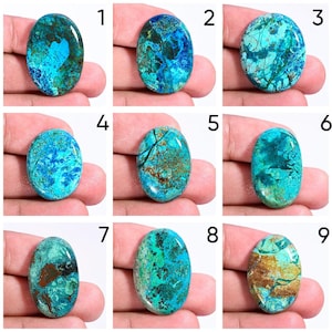 May include: Nine oval-shaped gemstones with a polished surface. The stones display a mix of blue, turquoise, and brown hues, with unique patterns and veining. Each stone is held in a hand, showcasing the natural variations in color and texture.