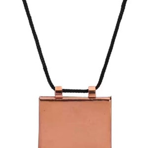 May include: A copper pendant necklace with a square pendant and a black cord.