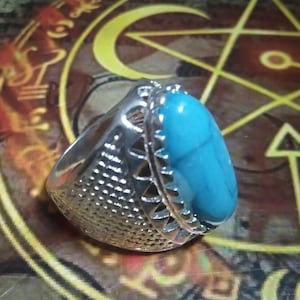 May include: A silver ring with a large turquoise oval stone set in a decorative silver band.