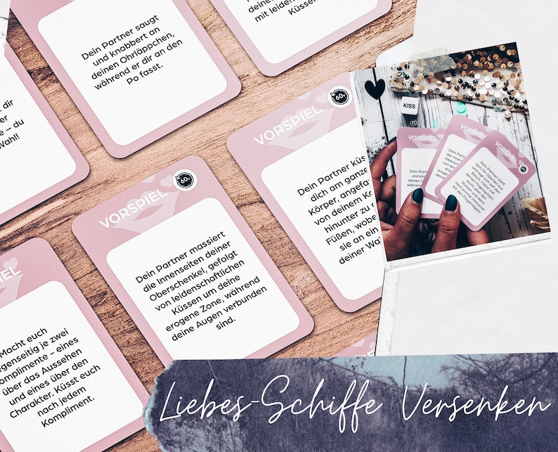 May include: Pink cards with the text "Vorspiel" and instructions for a couples game. The cards are on a wooden surface. The text on the cards is in German.