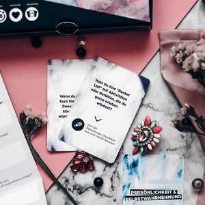 May include: Two cards from a game called "The Box of Meaningful Conversations". The first card is white with black text that reads "If you had a million dollars, what would you do with it?" The second card is blue with white text that reads "Personality & Self-Awareness".