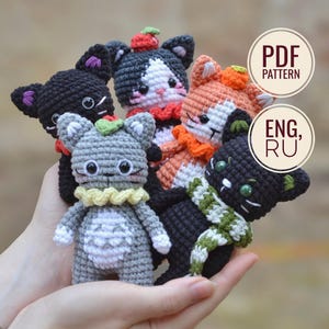 Peut inclure: Plusieurs poupées chats crochetées à la main, de couleurs variées, dont noir, gris et orange. Chaque poupée a des caractéristiques uniques, comme une écharpe ou un petit chapeau. L'image contient également le texte "PDF PATTERN" et "ENG, RU".