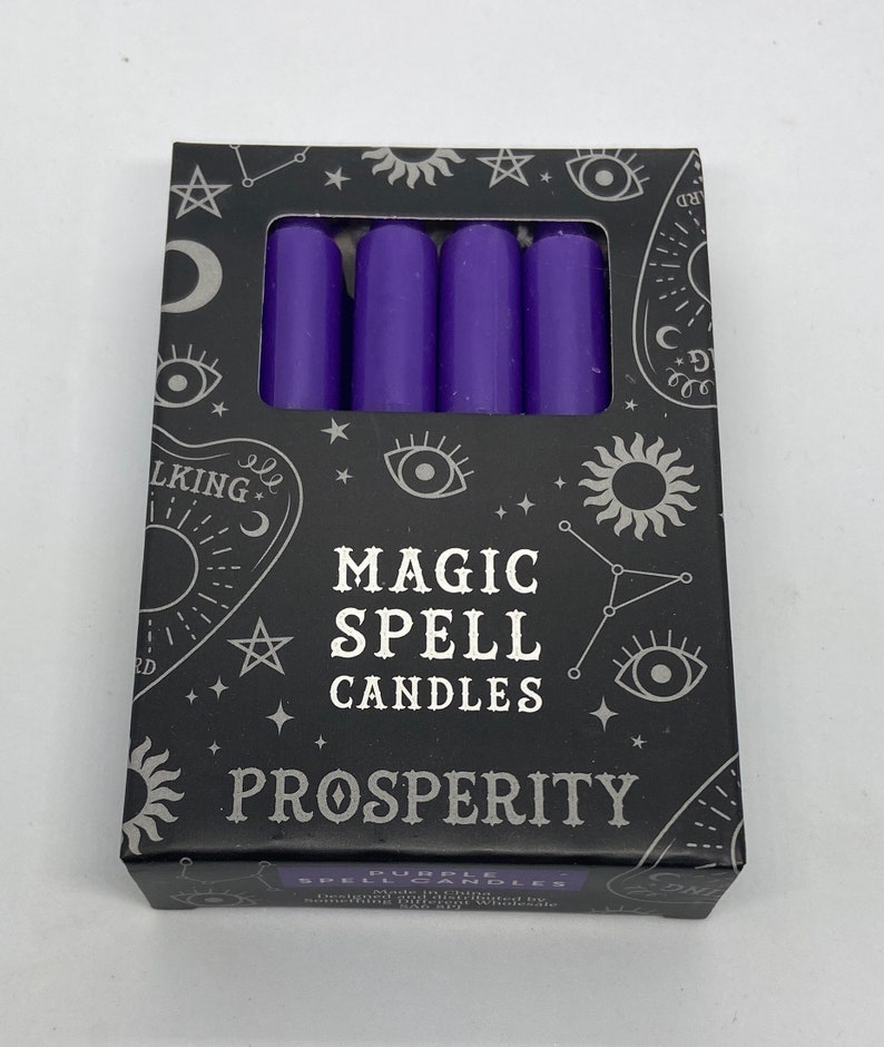 May include: A box of purple magic spell candles for prosperity. The box has a black background with silver stars, moons, and eyes. The text on the box reads "Magic Spell Candles" and "Prosperity".
