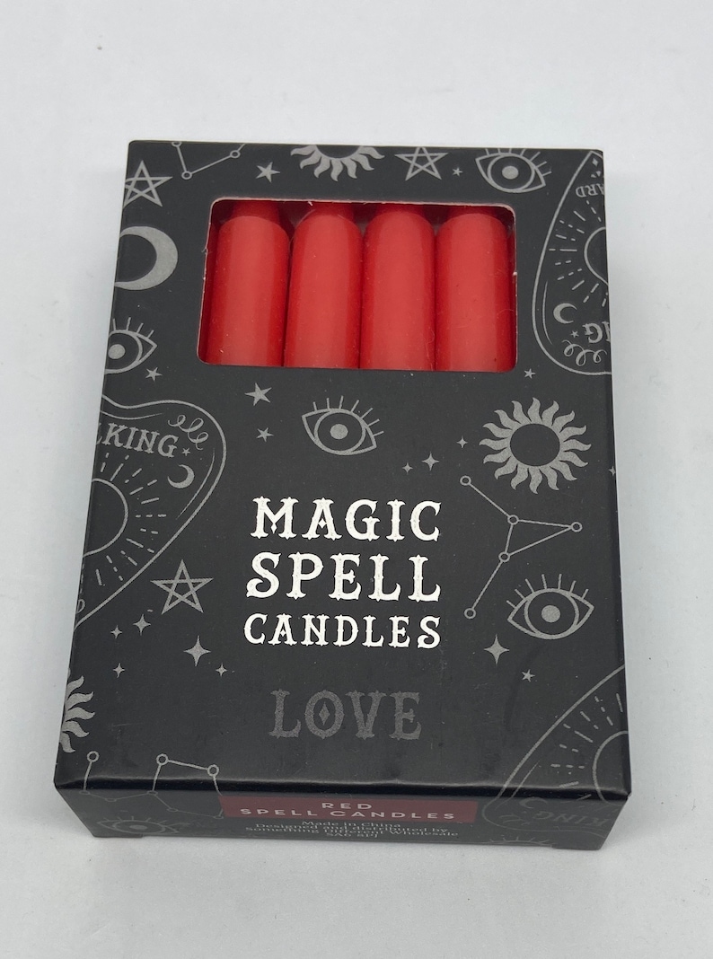 May include: A box of red magic spell candles for love. The box has a black background with silver stars, moons, and eyes. The text on the box reads "Magic Spell Candles Love".