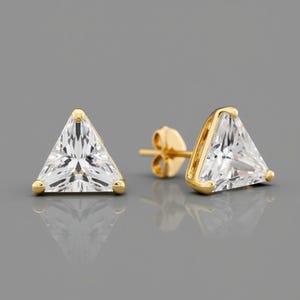 May include: A pair of gold triangle stud earrings with clear cubic zirconia stones.