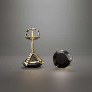Peut inclure: Une paire de boucles d'oreilles à clous avec une grosse pierre noire facettée sertie dans du métal doré. Une boucle d'oreille est assemblée, montrant la tige et le fermoir, l'autre est un gros plan du bijou.
