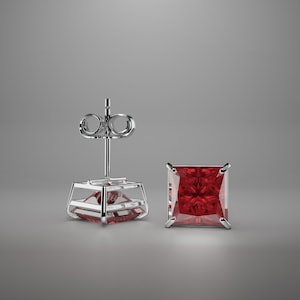 May include: A pair of silver stud earrings with a square red gemstone.