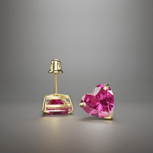 May include: A pair of gold heart-shaped stud earrings with pink gemstones.