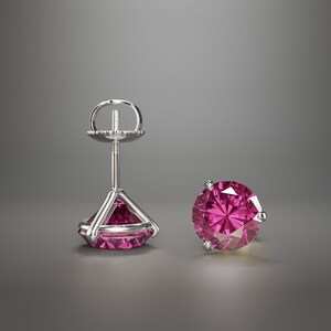 Puede incluir: Un par de pendientes de plata con una piedra preciosa rosa en cada uno. Los pendientes tienen un diseño sencillo con una pequeña piedra preciosa redonda engastada en un engaste de plata.
