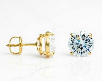 May include: A pair of gold stud earrings with large, clear, round-cut gemstones. The earrings are set in a classic four-prong setting, and the posts have a screw-back closure. The gemstones sparkle brightly against the gold.