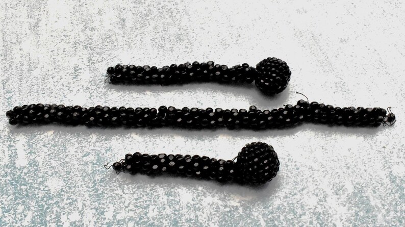 May include: Three black beaded necklaces with large round black beads at the ends.