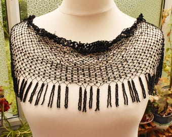 May include: Black beaded lace shawl with a fringe trim. The shawl is made of a delicate net-like fabric and has a scalloped edge.