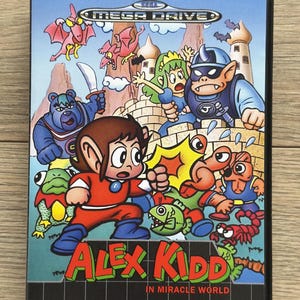 Könnte beinhalten: Eine Mega Drive Videospielhülle für "Alex Kidd in Miracle World". Das Cover zeigt eine Cartoonfigur in roter und blauer Kleidung, umgeben von Cartoonfiguren und dem Titel des Spiels. Das Sega-Logo ist sichtbar.