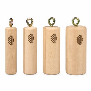 May include: Four cylindrical light-colored wooden blocks of varying diameters, each topped with a metallic eye bolt. Each block features a laser-engraved logo with the text "IM WORKSHOP 19/50" on the front surface, showcasing a natural wood grain.