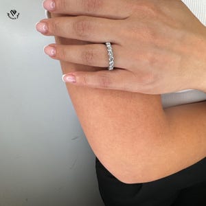 May include: A silver eternity band with a row of round, clear gemstones.
