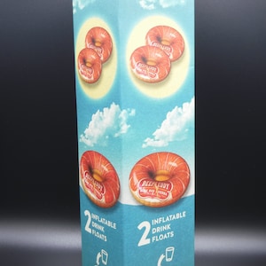 May include: A box of two inflatable drink floats shaped like donuts. The donuts are red and white with the text "Deep Eddy Vodka" printed on them. The box is blue and white with the text "2 Inflatable Drink Floats" printed on it.