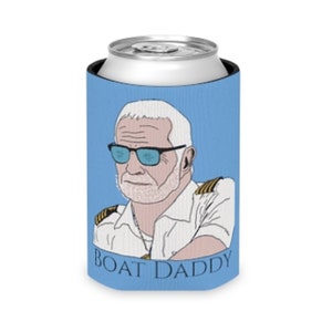 May include: A blue and white can cooler with a cartoon illustration of a man with a white beard and sunglasses. The text "BOAT DADDY" is printed on the cooler.